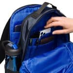 a hand putting a phone in a backpack