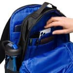 a hand putting a phone in a backpack